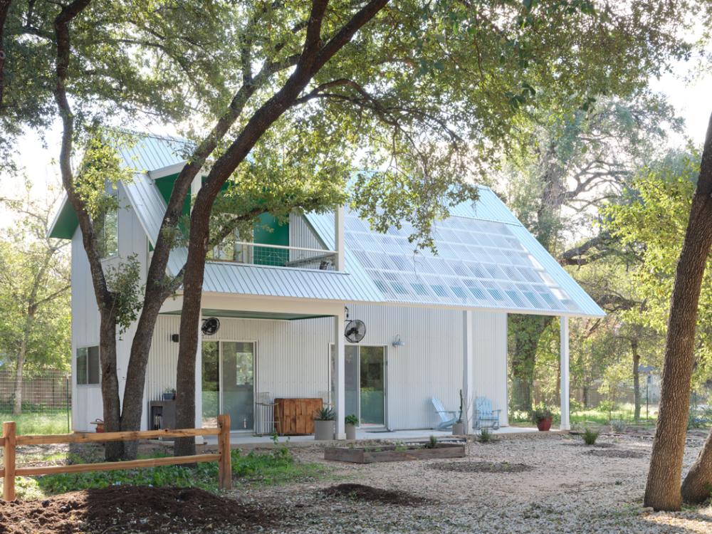 A white house with solar panels on the roof.